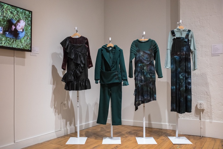 Row of four mannequins displaying a collection of dark green clothing.