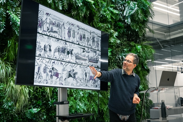 Bill Kartalopoulos points to a screen displaying a Medieval scroll with sequential artwork.