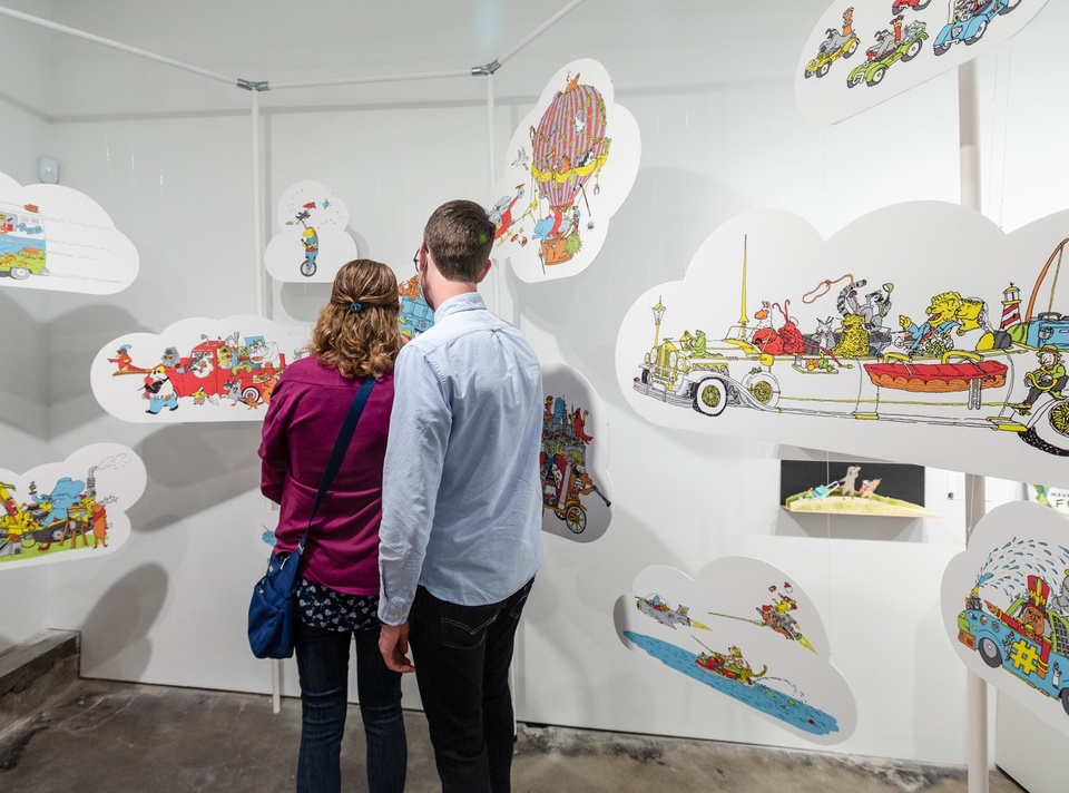 Multiple cloud cutouts of illustrations hang from the ceiling depicting anthropomorphic animals