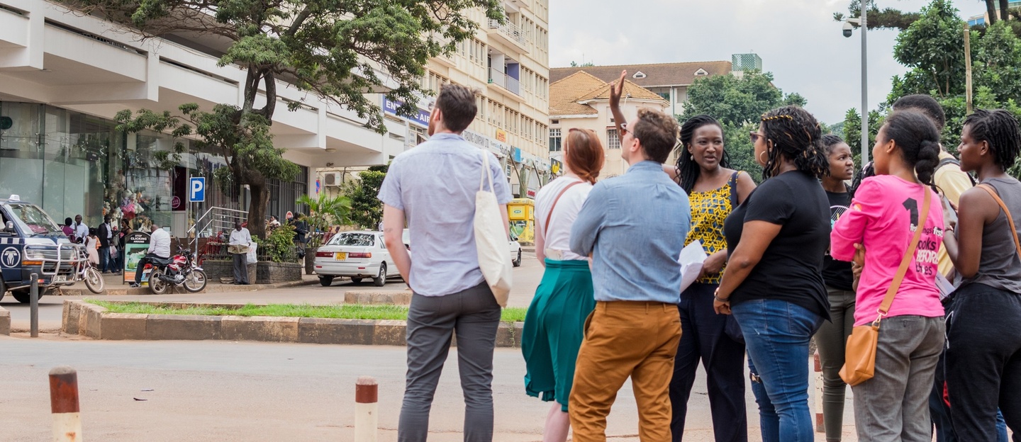 Group of people look across the street at a building in a foreign country.