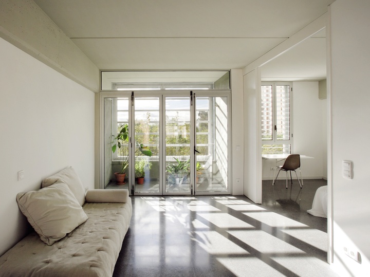 Internal view of an apartment with minimal furniture and large floor to ceiling windows