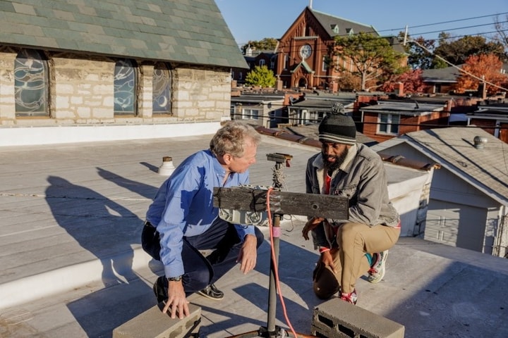 WashU graduate and professor look over air monitoring equipment on a roof in south St. Louis