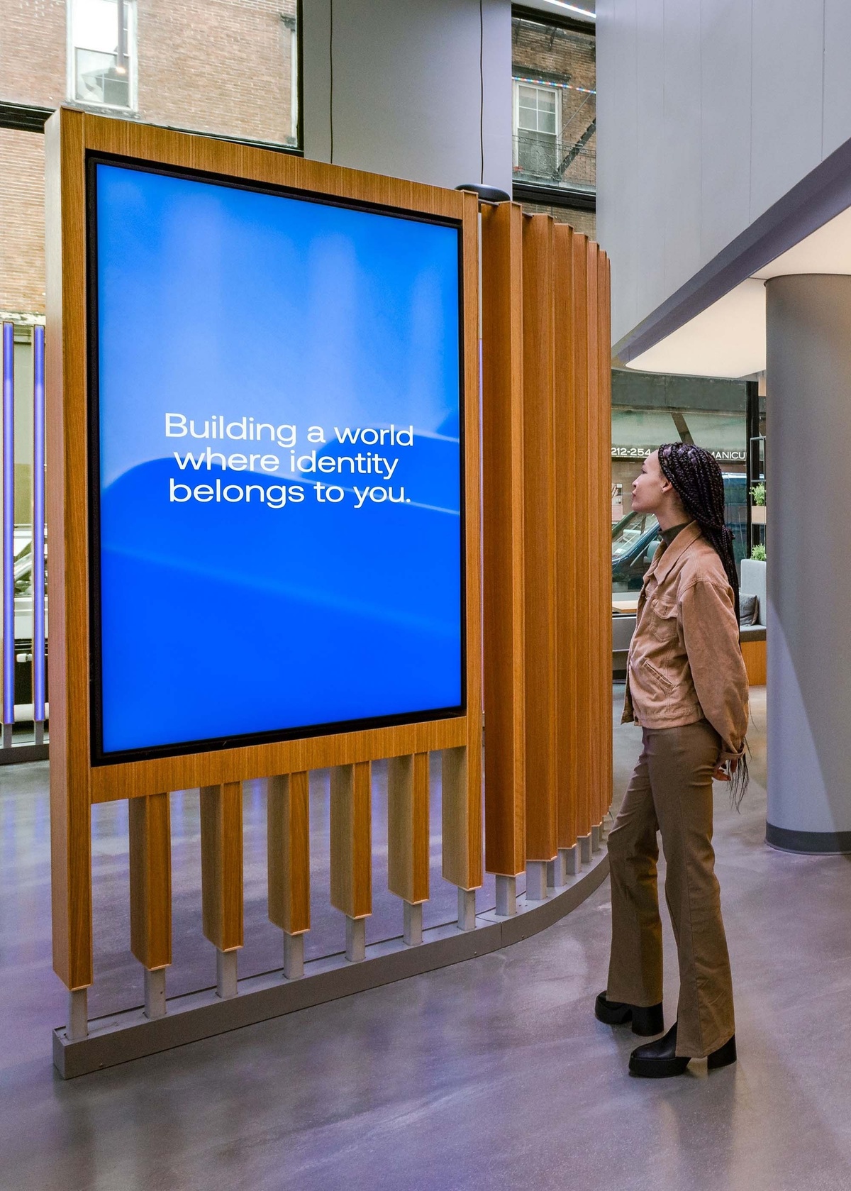 Young woman looking at content on digital screen on the installation that says "Building a world where identity belongs to you"