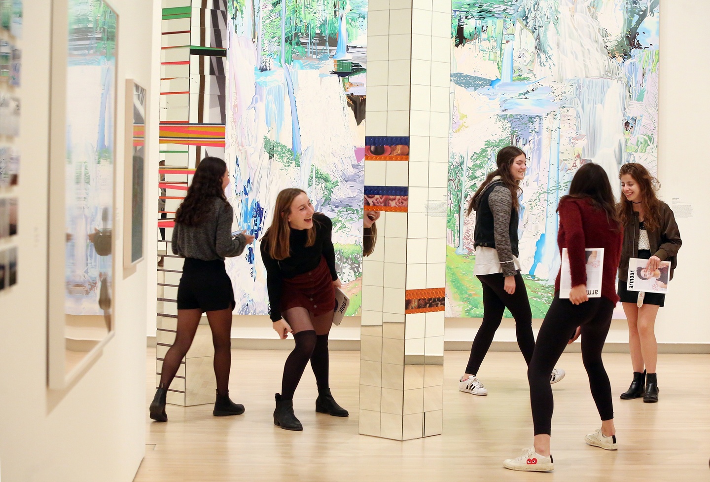 People smiling and playing around a mirrored column