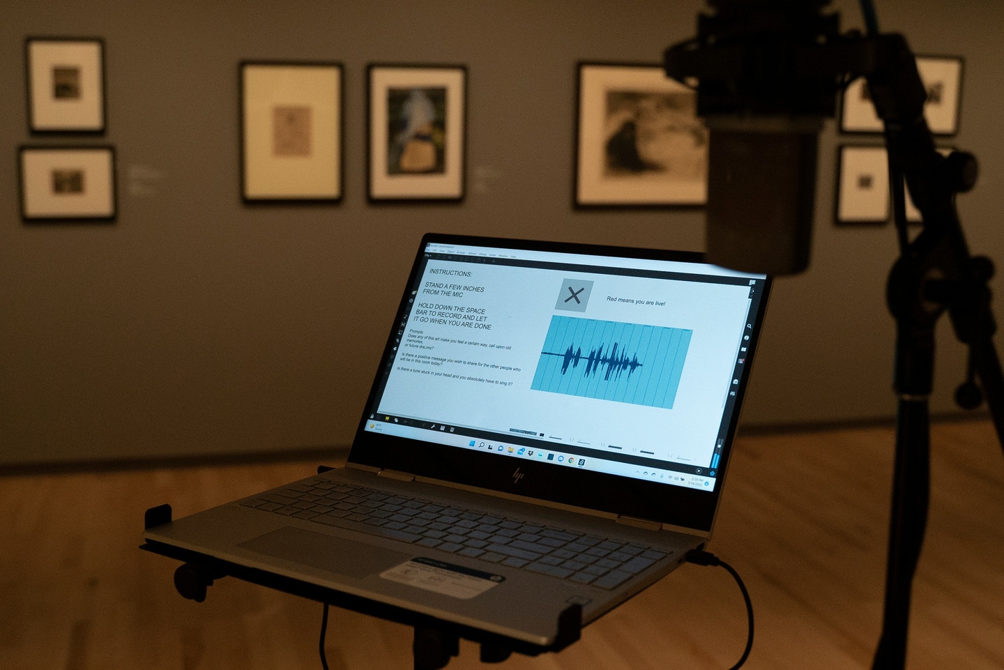 Color photo of a laptop and microphone in a gallery setting