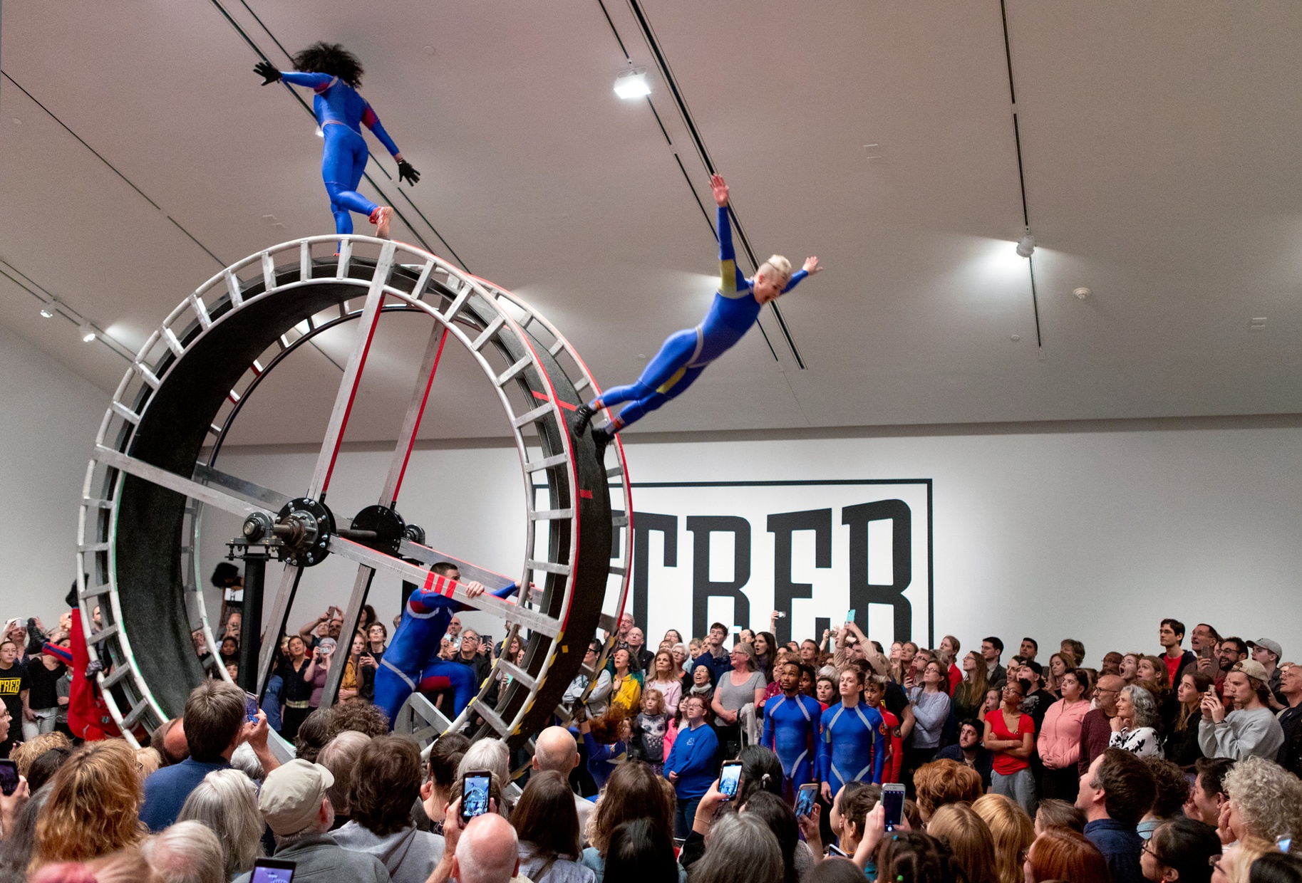 A dancer flies off a giant hamster wheel before a standing-room-only crowd