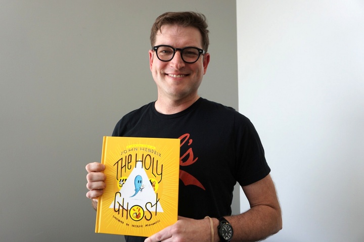 Headshot of John Hendrix holding a copy of his book, The Holy Ghost.
