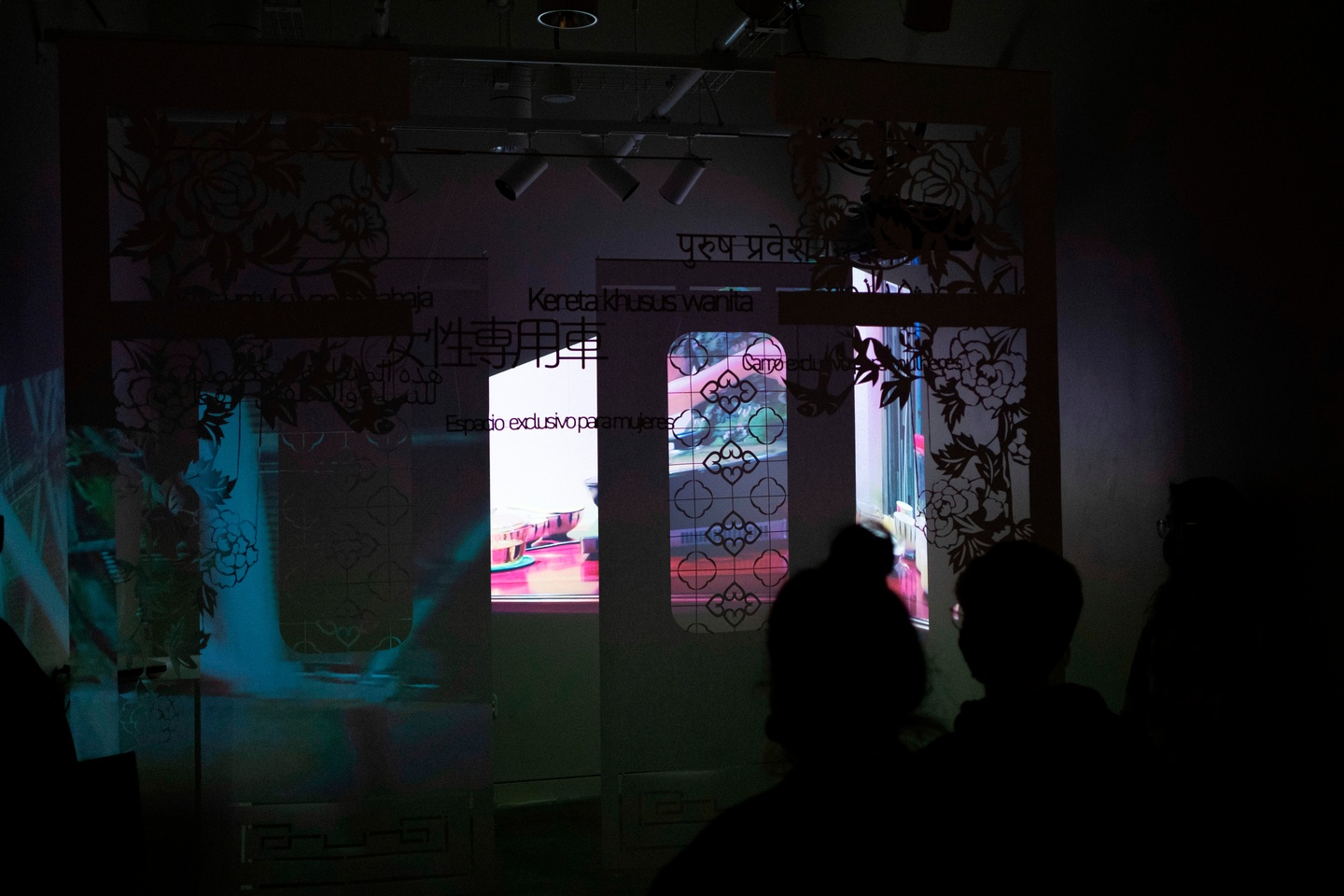 Installation room with projections on floral and text paper cutouts 