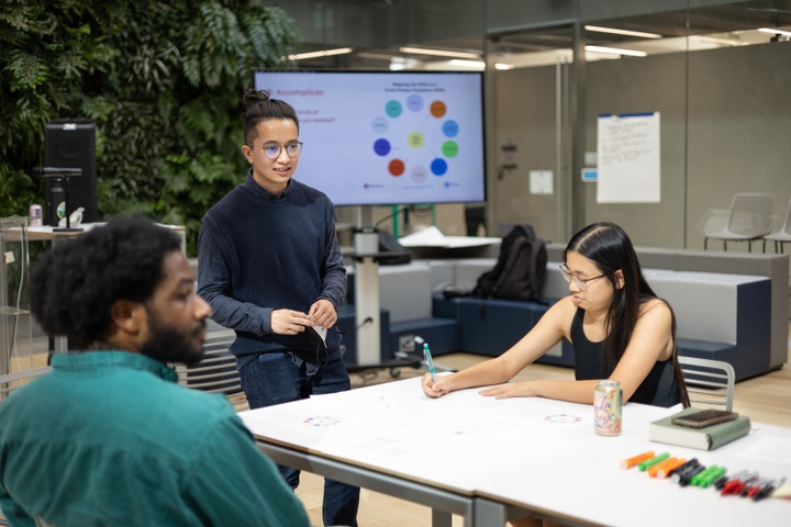 Kong stands at the head of a table of students in Kuehner Court.