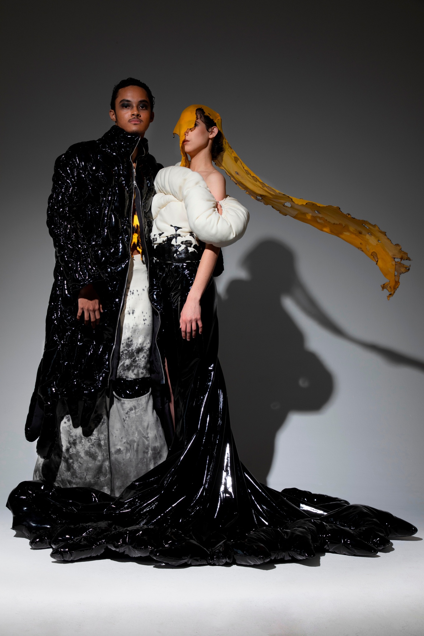 Two models wearing black and white with yellow accents outfits from the collection, Spiritual Erosion