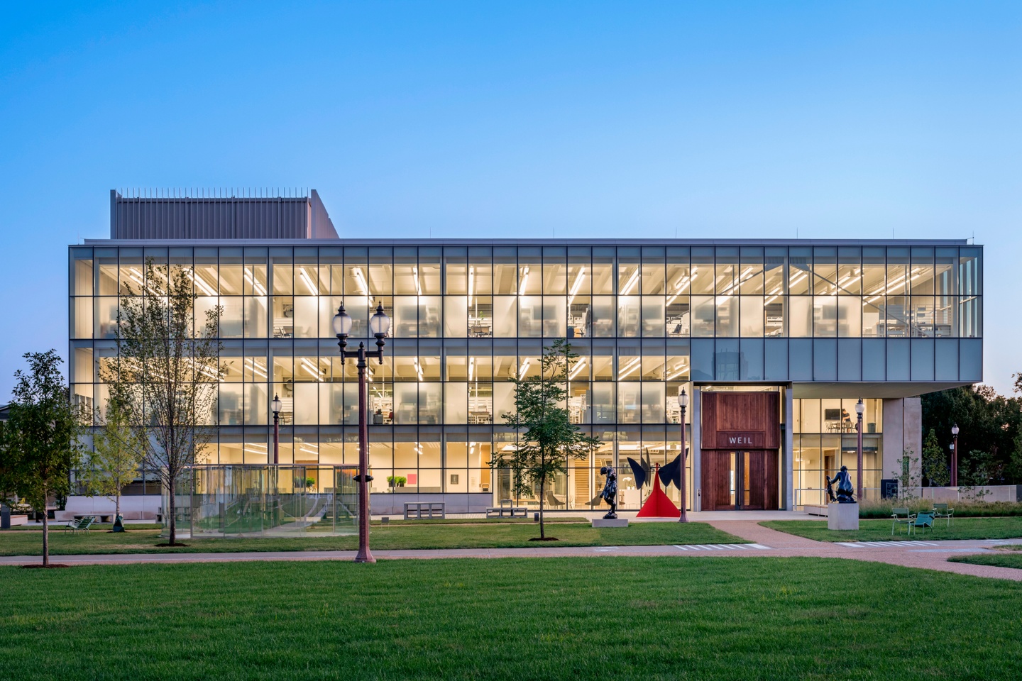 Photo of the exterior facade of the three-story Weil Hall, illuminated at dusk.