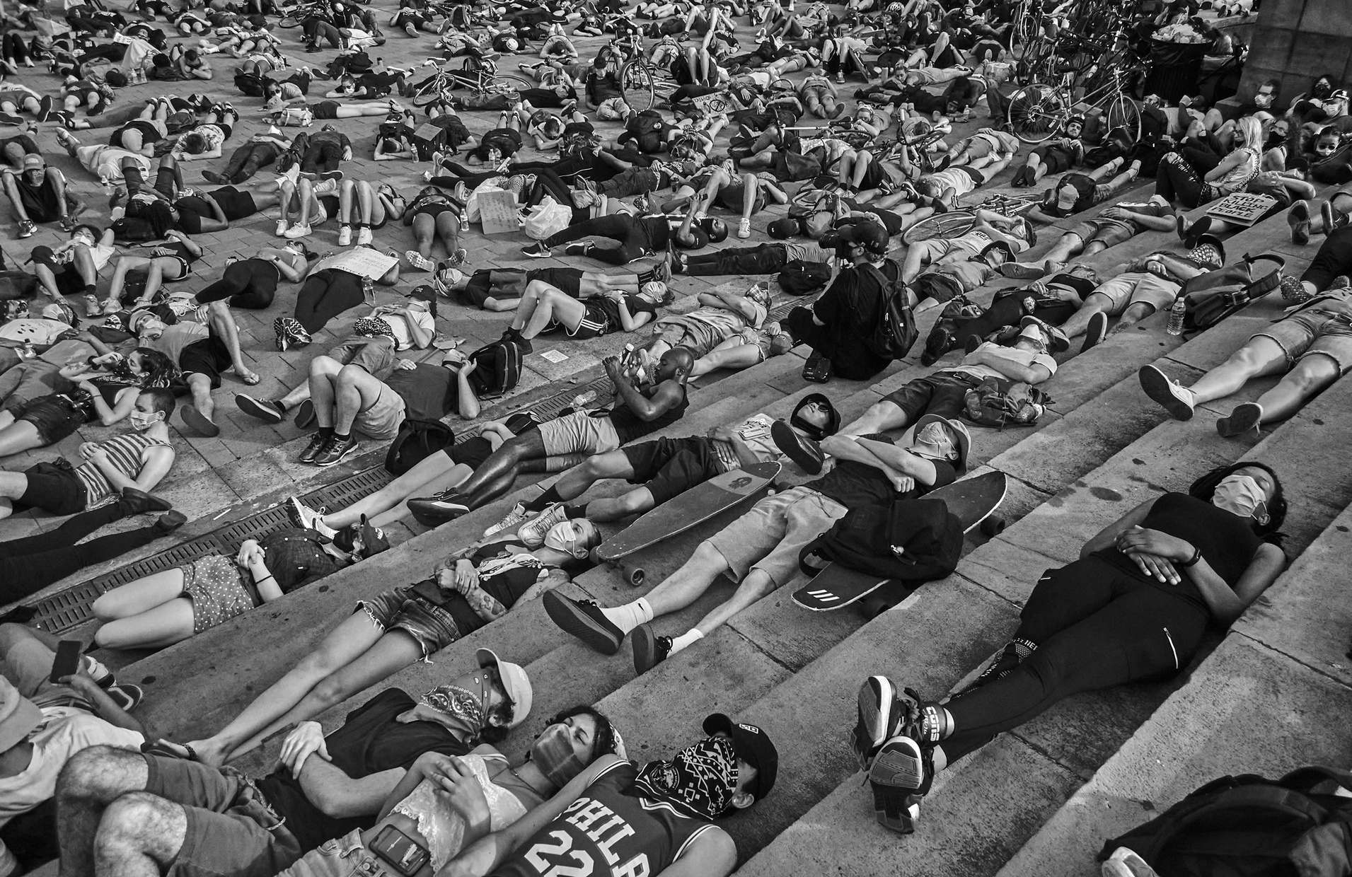 A black and white photograph of protesters lying down on concrete stairs.