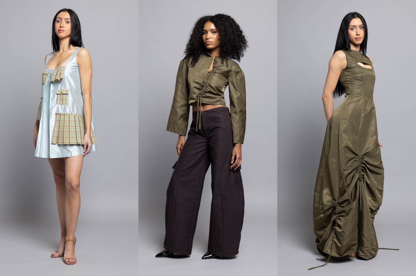three models showcasing a collection, L to R: model is wearing a short sleeveless silk light blue dress with pleated plaid pockets and accents, the second model is wearing wide leg black pants with a long sleeve olive green silk cropped shirt with ruching down the front, the third model is wearing a floor length olive green silk dress with ruching along the hem 