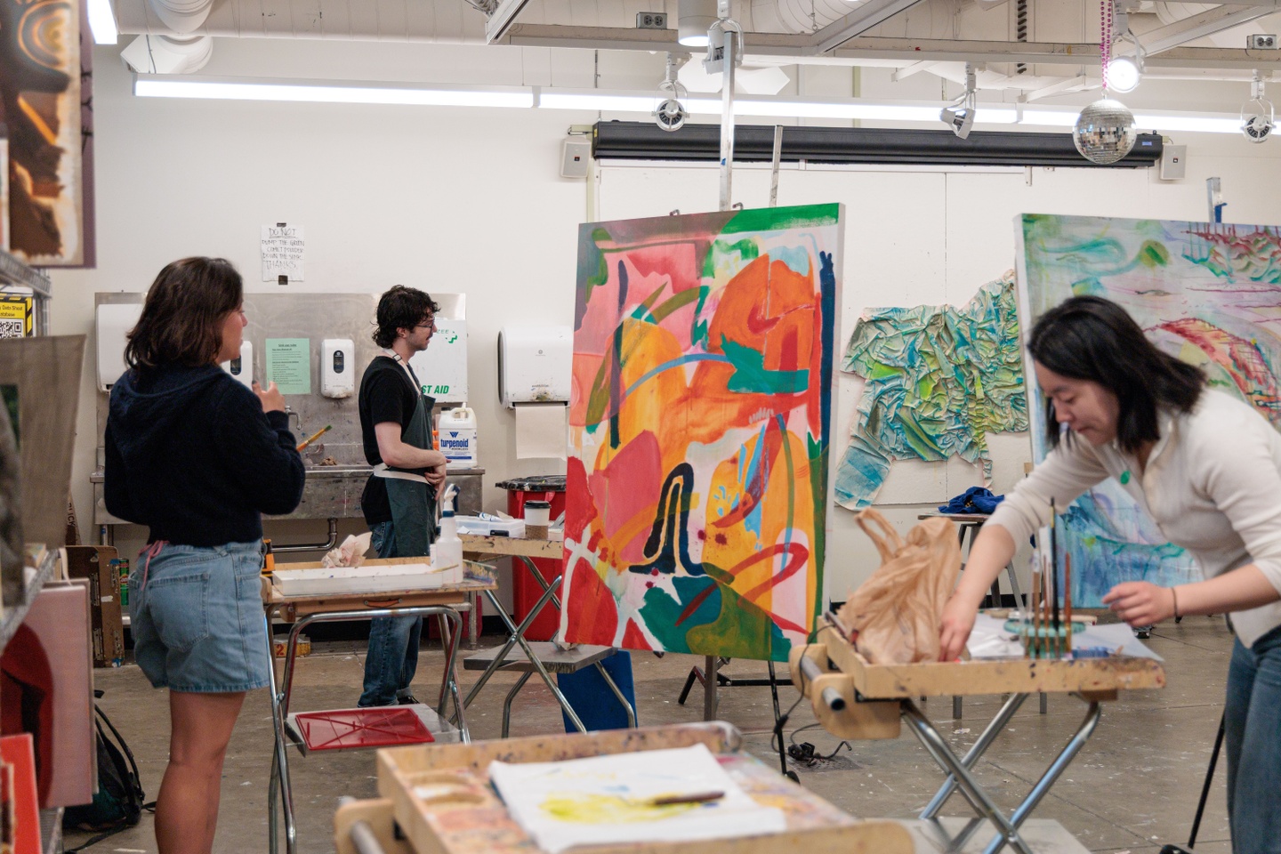 three students working on art in a studio