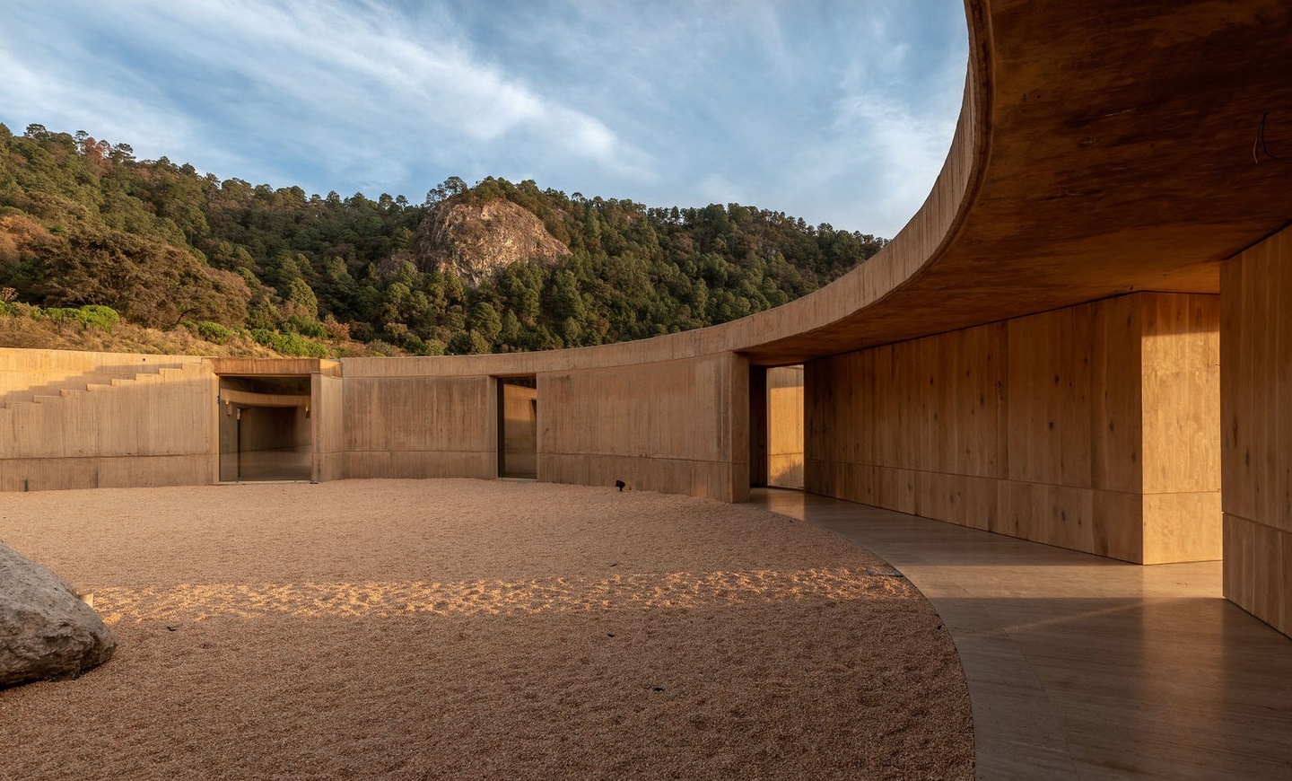 image of sand courtyard of earthen building with green mountains in the background