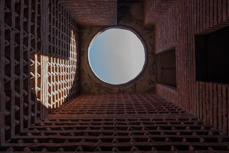 Detail shot of a round opening to a building, looking at the sky, surrounded by intricate brick work.