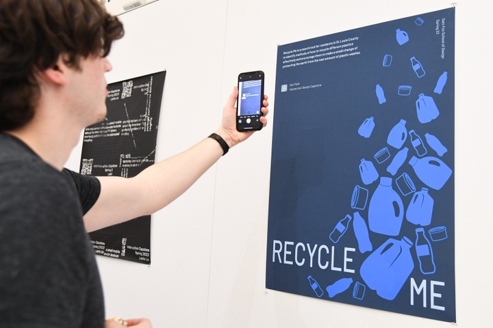 A student scans a QR code on Seri Park's poster RECYCLE ME