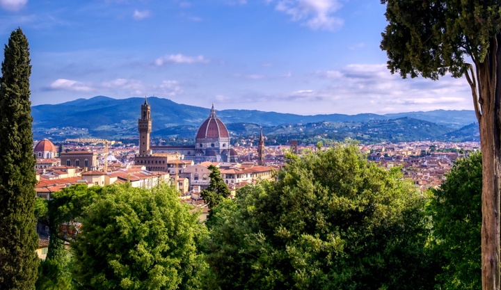 Skyline view of Florence, Italy with cathedral in center and trees framing the view.