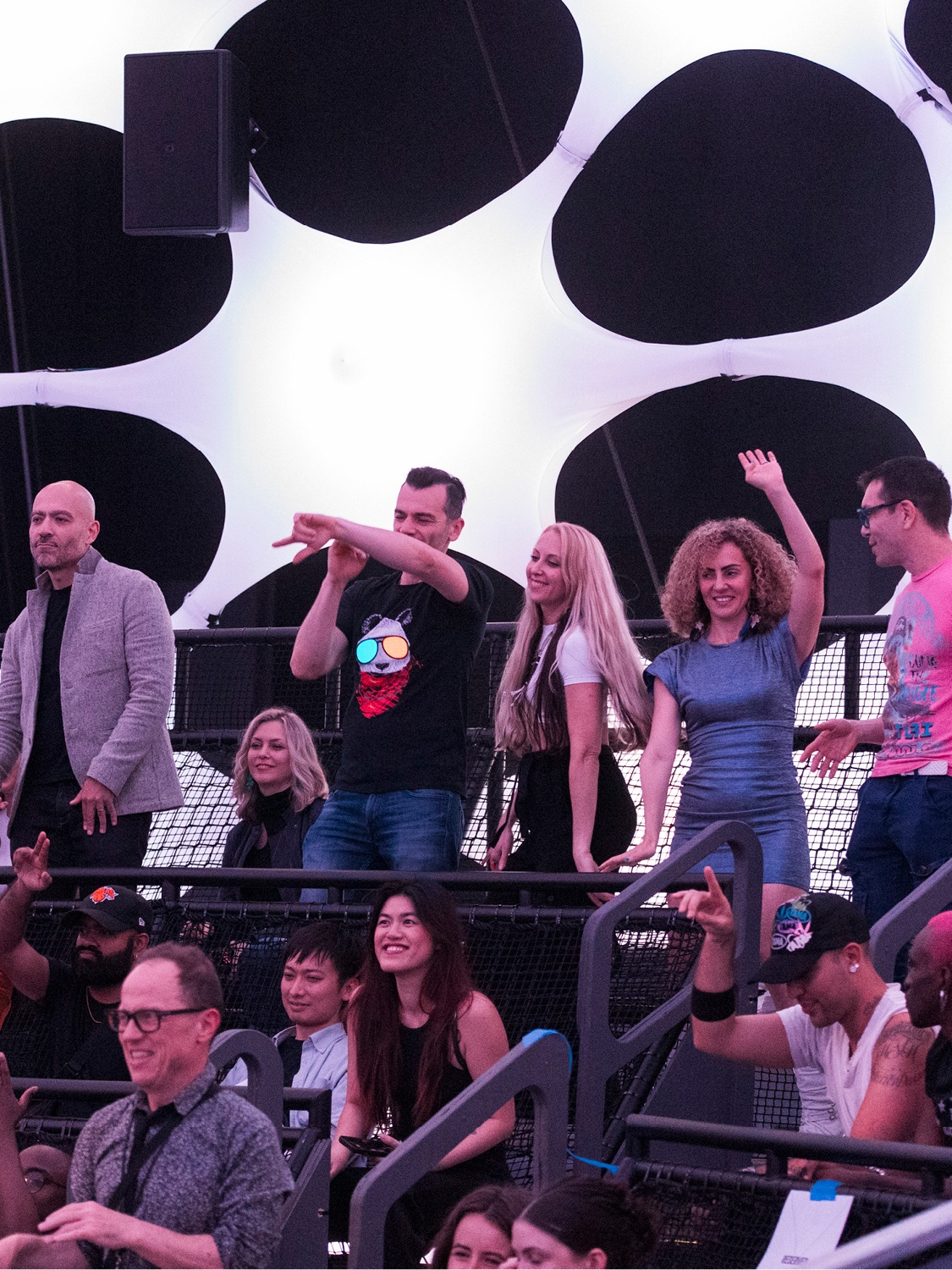 Visitors to Sonic Sphere stand and dance with their hands in the air. Behind them, the fabric of the sphere glows with a white light.