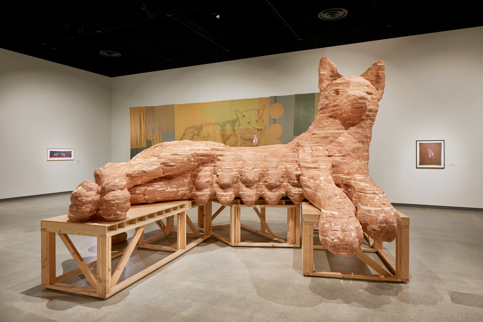 A large, carved sculpture of a reclining wolf with ten, full teats on it's stomach. 