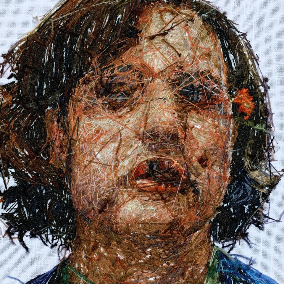 Hand embroidered portrait of a figure with dark hair that's about chin-length. The reverse side of the embroidery is shown, exposing the stitches and creating textural interest.