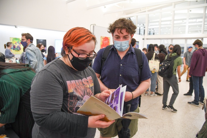 Two students flip through a book by Kade Becker