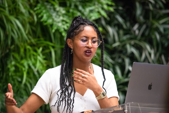 Hillawi Abraham speaks in front of a living green wall.