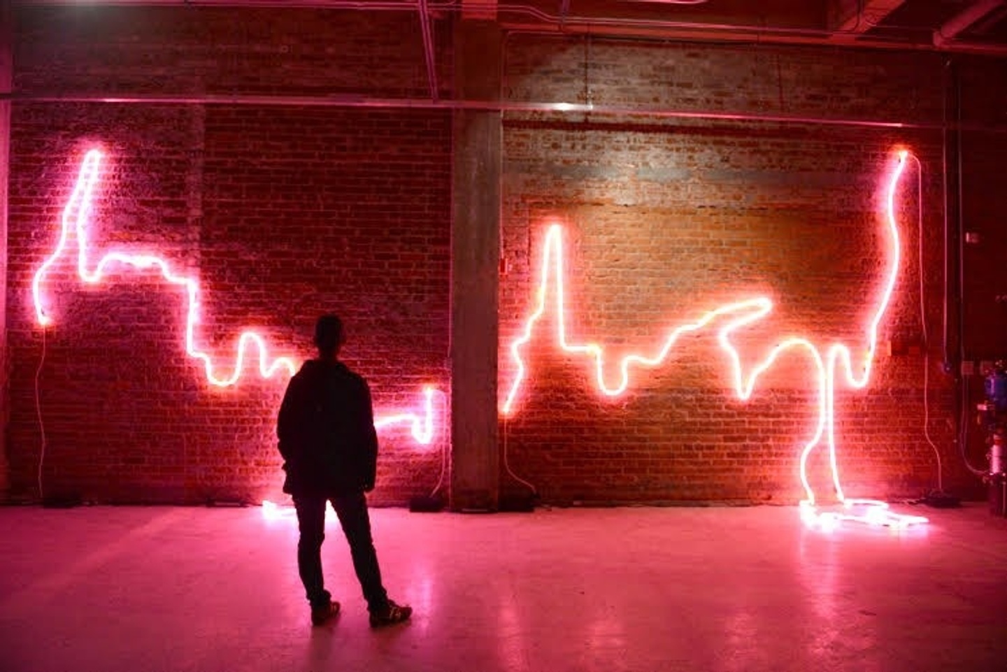 Man stands in front of jagged pink neon lights on the wall