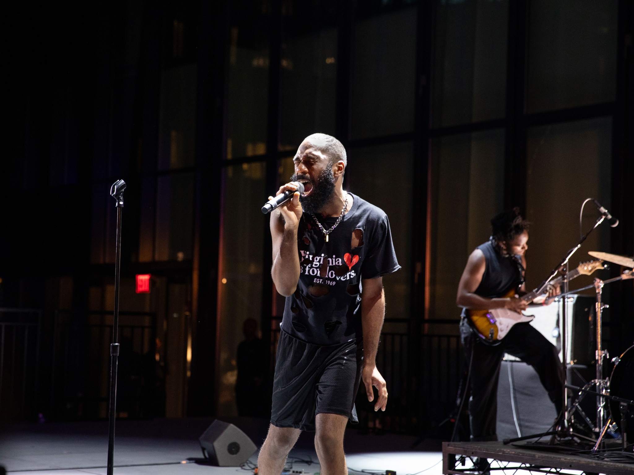 Man singing into mic on dramatically lit stage.