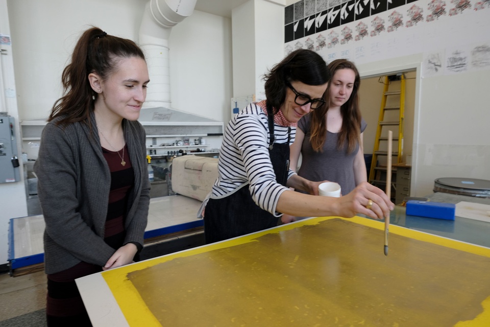 Artist Diane Guerrero-Maciá making a monotype while two students watch