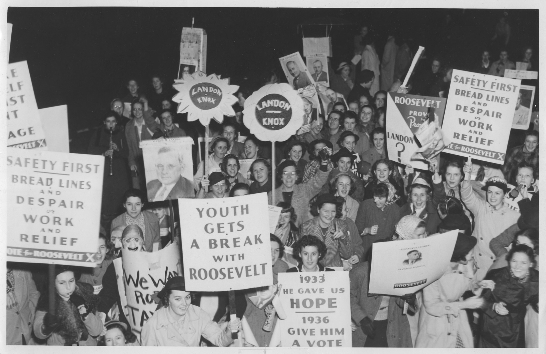 A black and white photograph depicts a crowd of light-skinned young women who are smiling and holding signs in support of Franklin D. Roosevelt and Alf Landon.
