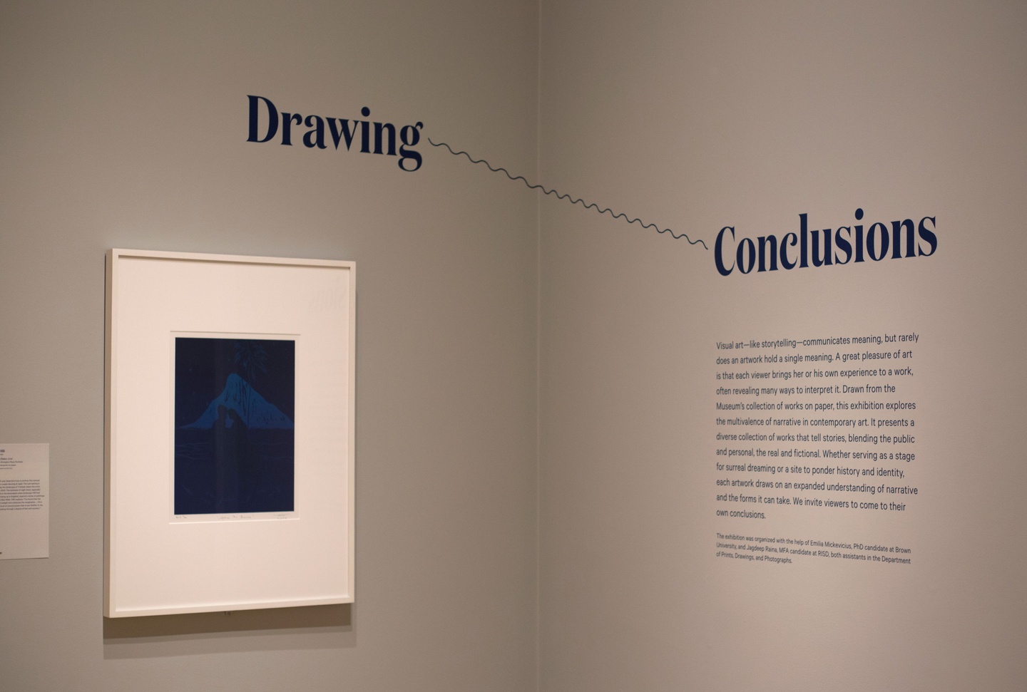 The corner of a gallery space with light gray/cream walls, with the words "Drawing Conclusions" connected across the corner with a wavy line. To the left is a framed artwork; to the right, some wall text.