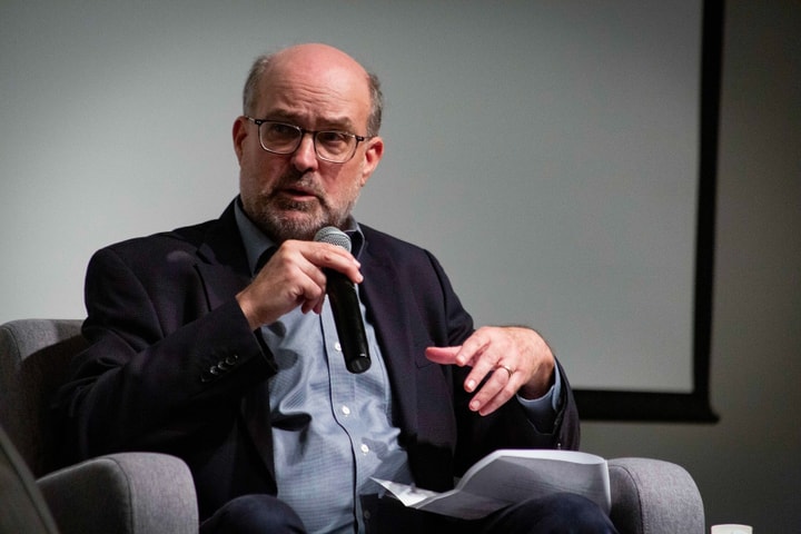 Seated man talking and holding a microphone