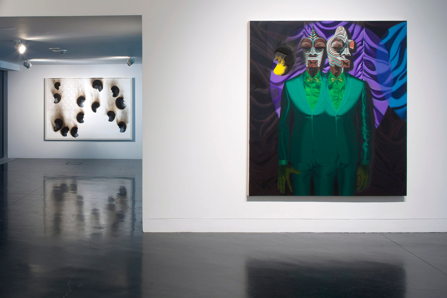 An abstract painting of two Black men in green suits merged together with a black, blue, and purple background hanging on a white wall.