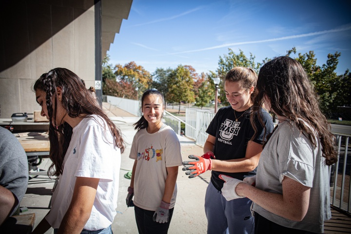 Students smile while putting on gloves for the workshop