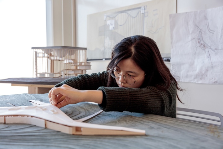 Student works on a large-scale architectural model on a topographic base.