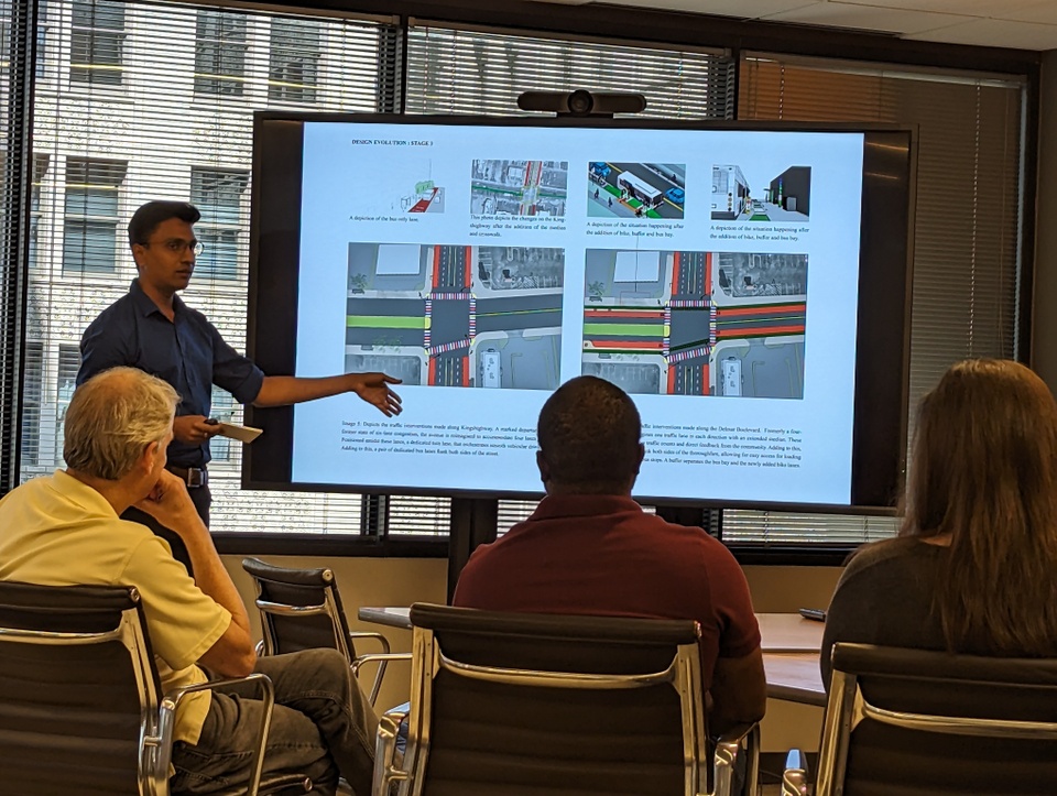 Graduate student standing in front of screen presenting his work 