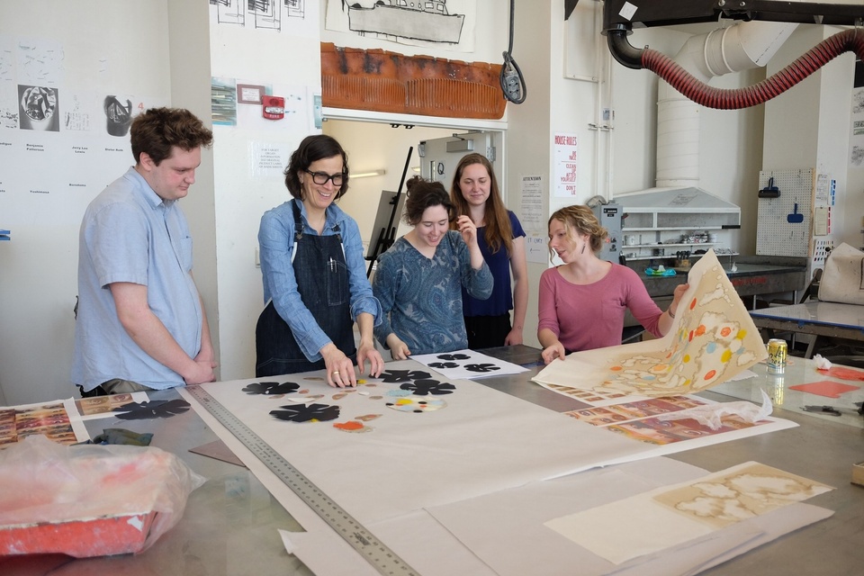 artist with student helpers in print shop