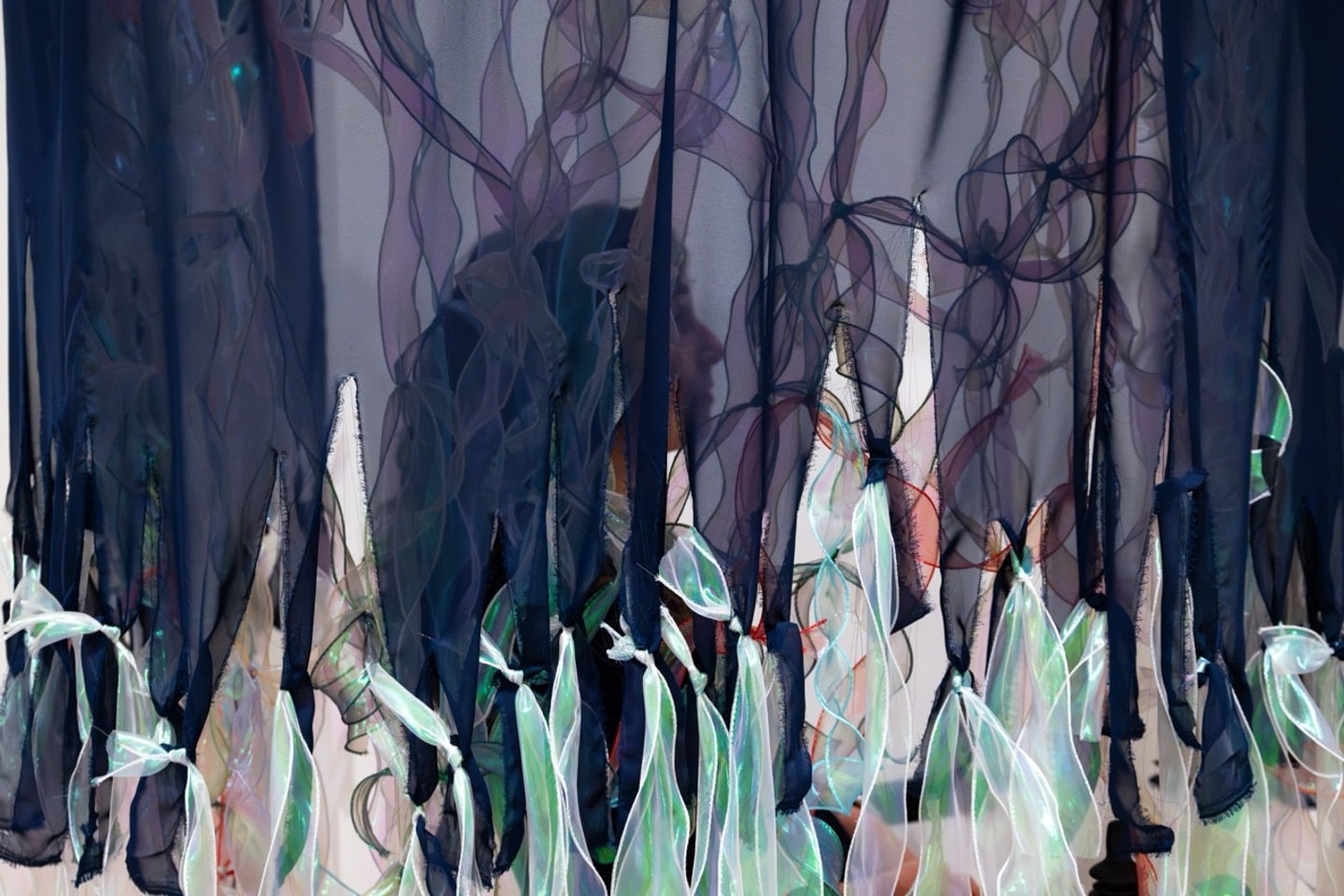 close up of a wheelchair surrounded by a curtain made of chiffon and ribbon in a gallery