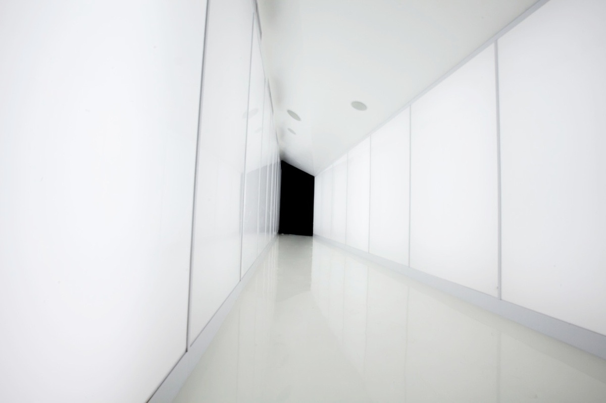 Image of white, sleek hallway that leads to a black entrance