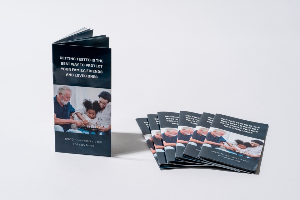 A stack of blue self-test instructional booklets lies next to an open booklet.