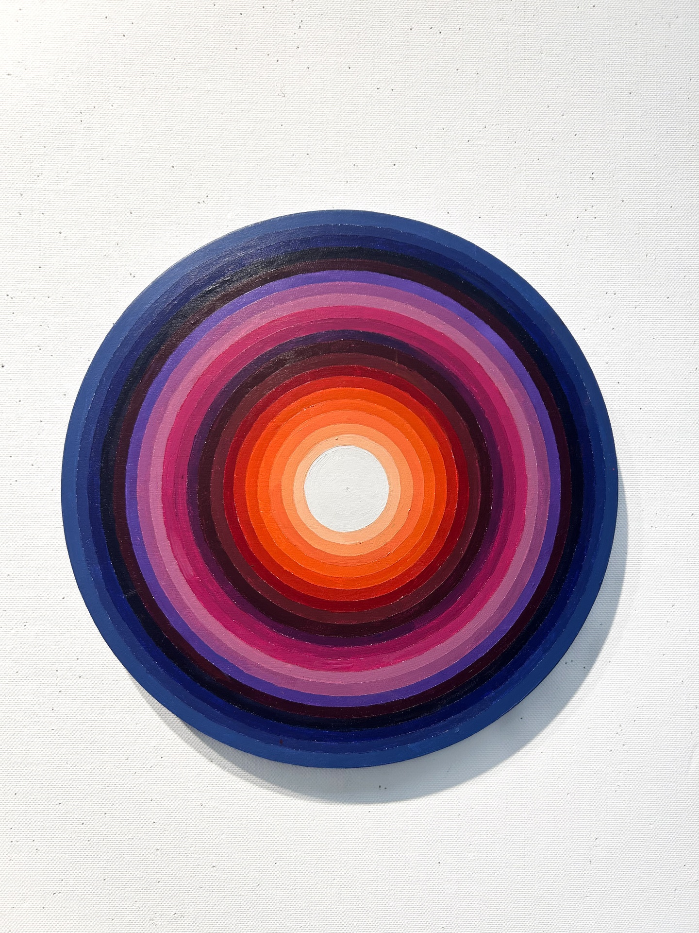 A circular painting made of concentric rings of differing colors. 