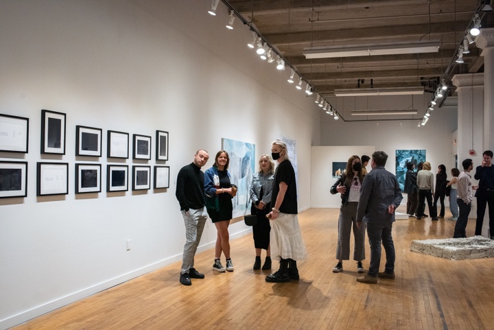 Gallery space filled with visitors, displaying 2D and 3D artworks.