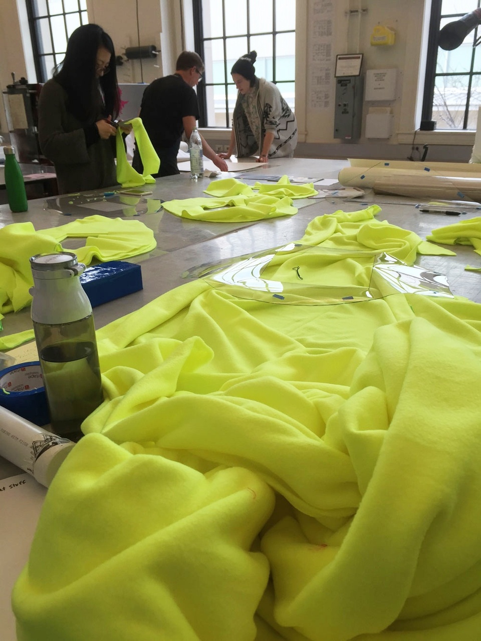 bright yellow fabric in foreground with people working in the background