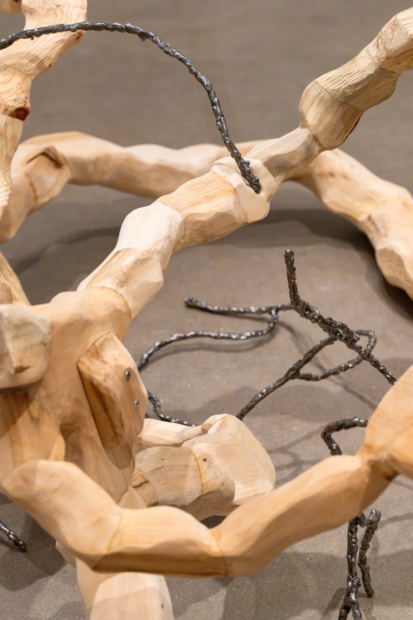 carved wooden pieces fitted together in an endless twisted configuration on display in a gallery