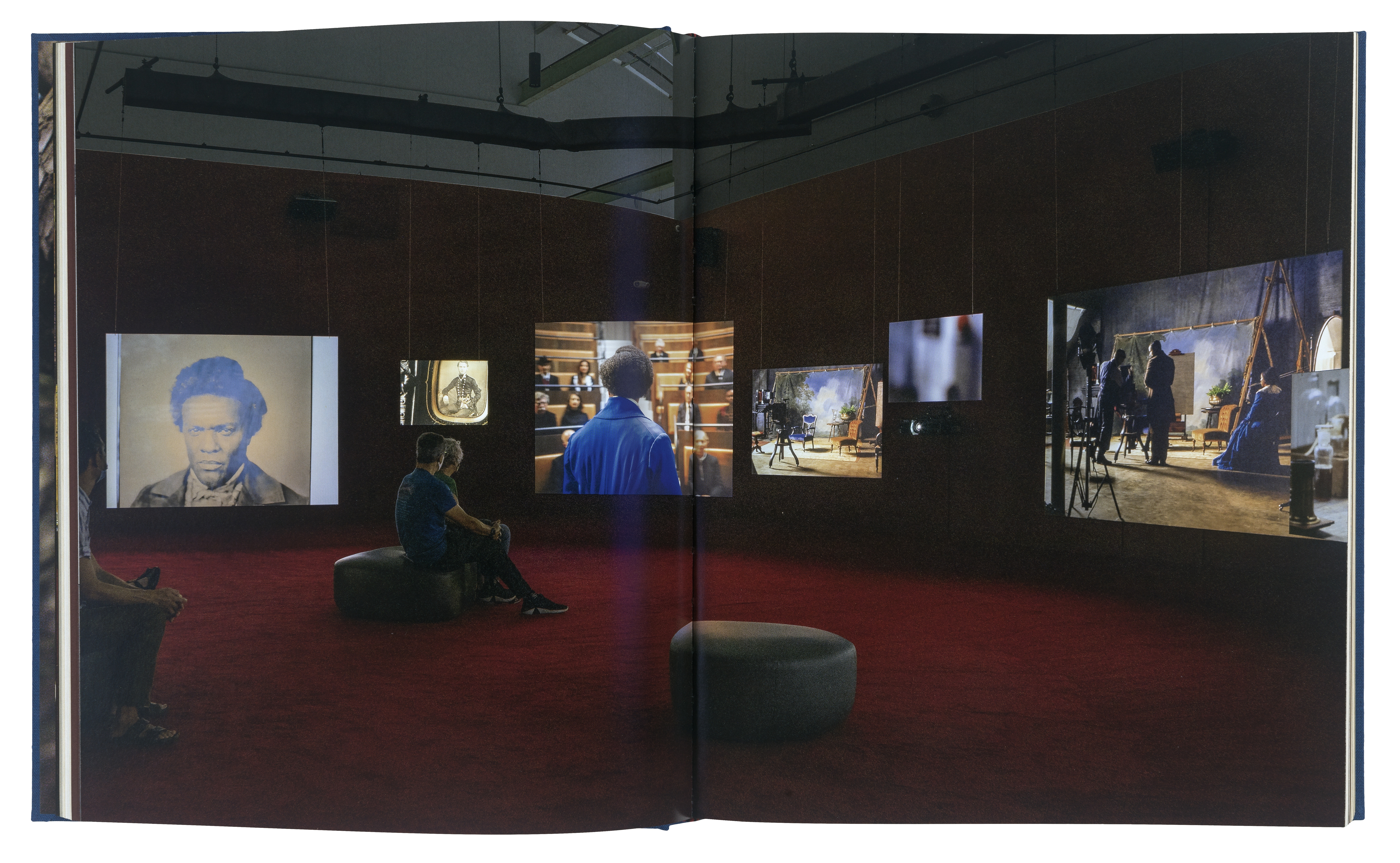 A spread of one of the pages of Lessons of the Hour, featuring a dark gallery with several videos playing on screens.