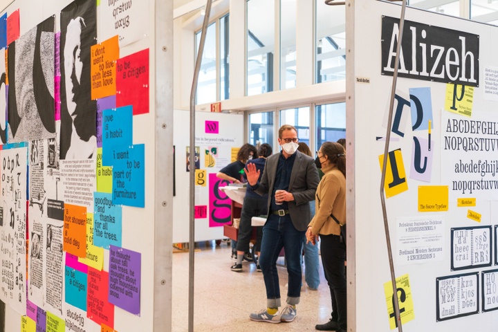 Faculty stand and chat in front of a display of sample typography.