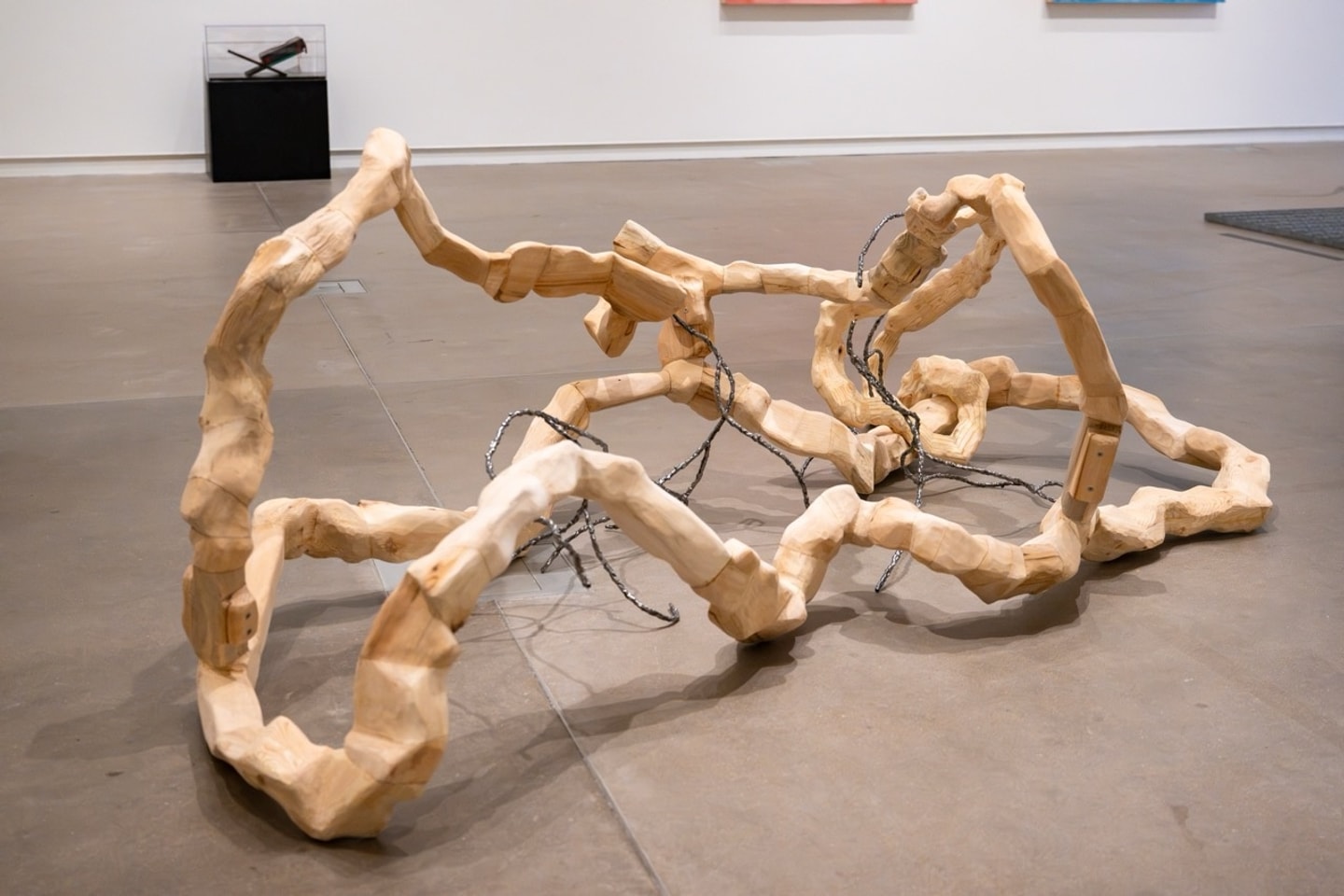 carved wooden pieces fitted together in an endless twisted configuration on display in a gallery