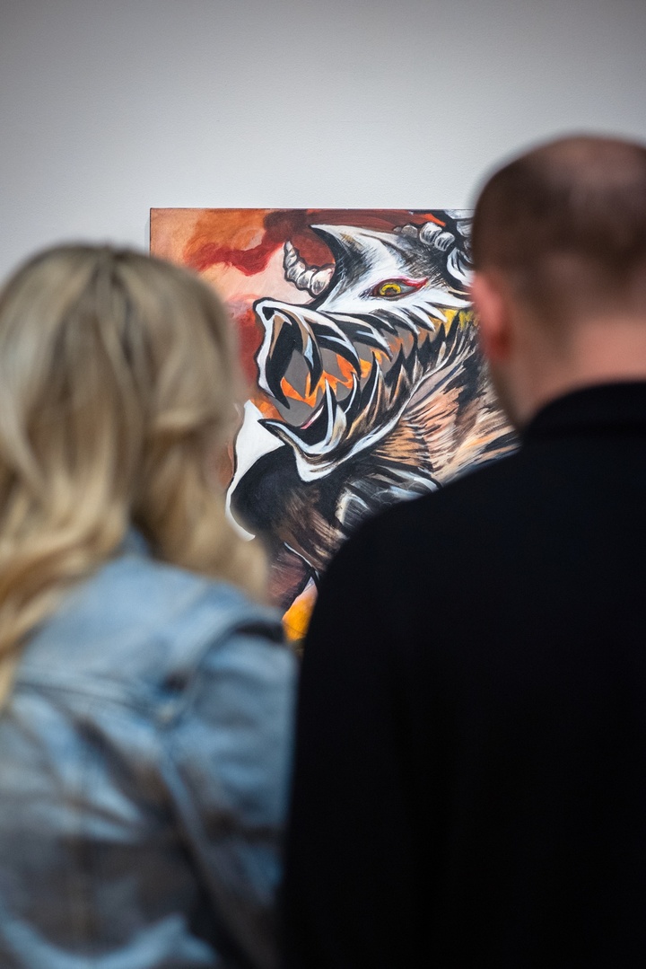 Over the shoulder view of a grey and orange painting of a skeletal-looking dragon-like creature snarling.