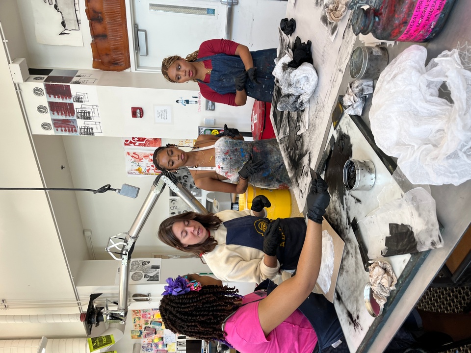 student printmakers inking plates and helping with artist project